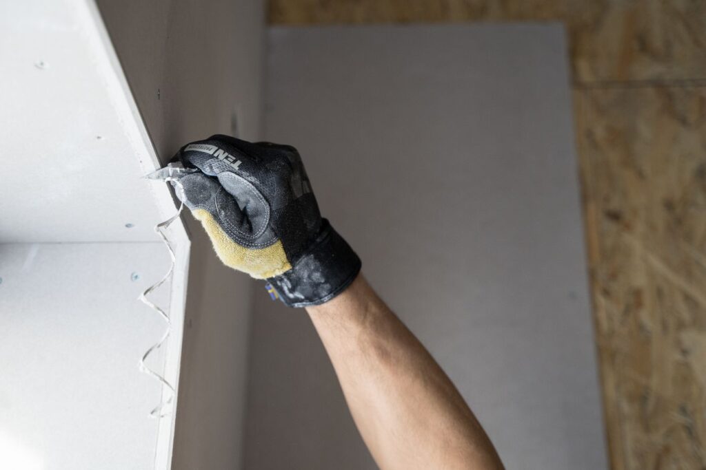 Application d'enduit de rebouchage avec des gants de protection sur un mur