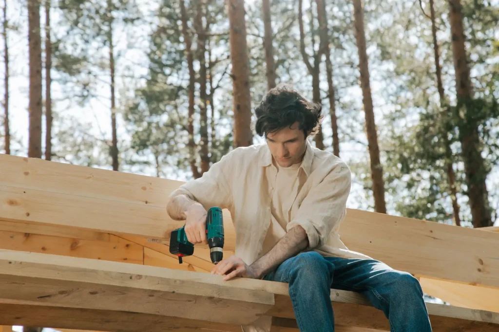 Perceuse-visseuse utilisée pour fixer un poteau en bois en extérieur