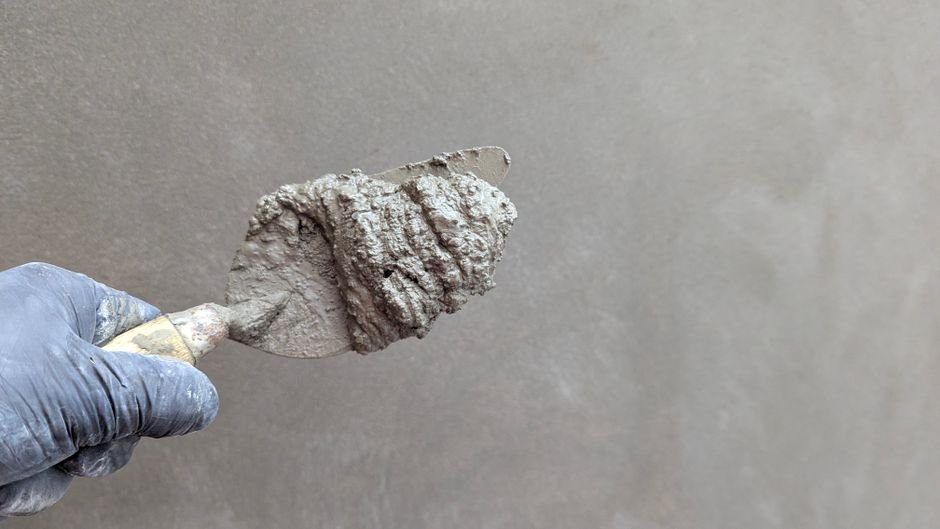 Main tenant une truelle avec de l'enduit pour reboucher un mur