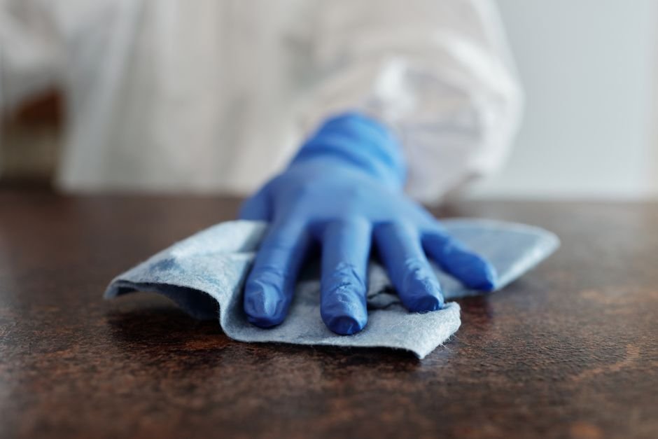 Main gantée nettoyant une surface avec un chiffon