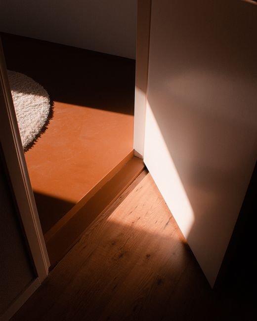 Lumière passant sous une porte ouverte sur parquet