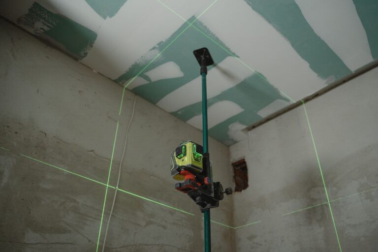 Niveau laser vert sur perche projetant ses lignes